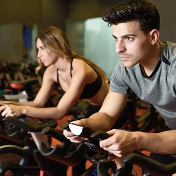 a man and a woman pedal intensely in a spin cycling class